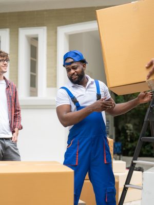 Man movers worker in blue uniform unloading cardboard boxes from truck for moving house service
